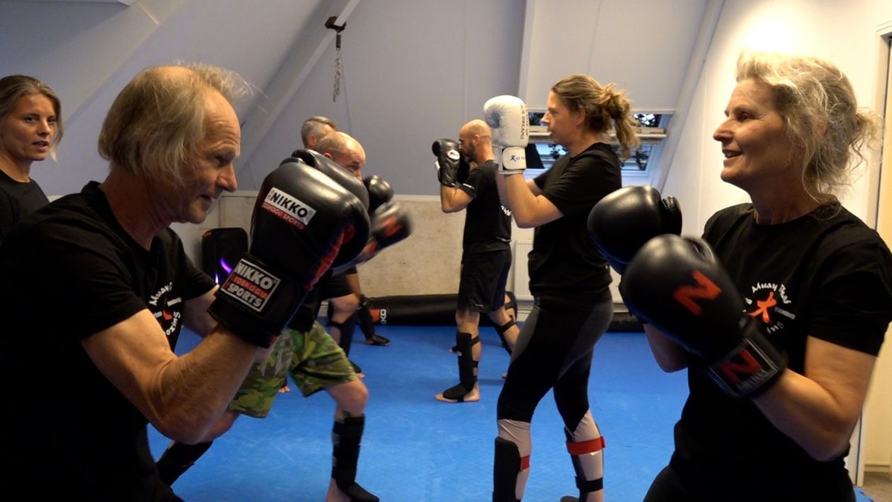 Nico (71) en Renske (62) sparren met elkaar. Trainster Krista Fleming kijkt achter hen toe. Foto: Omroep Gelderland