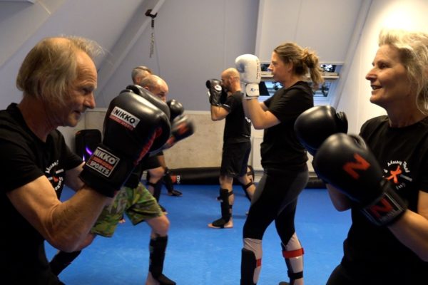 Nico (71) en Renske (62) sparren met elkaar. Trainster Krista Fleming kijkt achter hen toe. Foto: Omroep Gelderland